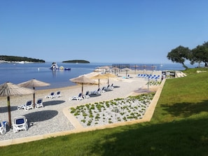 A beachside resort with sun loungers, umbrellas, and a clear view of the sea. -  Funtana Apartments Budinjaš  (FUNTANA)