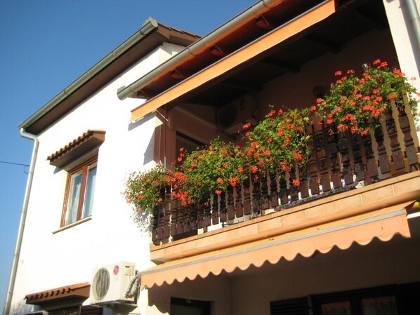 Ein Gebäude mit einem Balkon, geschmückt mit roten Blumen, und traditioneller Bauweise.