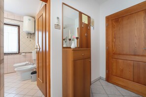 Ein Badezimmer mit Toilette, Bidet und einem Holzkabinent mit Spiegel.