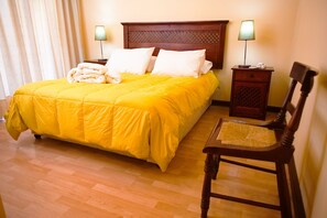Cozy retreat with a neatly made bed, two bedside tables, and a comfortable chair.
