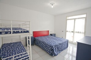 A dormitory room with bunk beds, a desk, and a window with curtains.