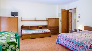 Een slaapkamer met een bed, een bureau, een stoel, een kledingkast en een televisie.