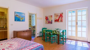 Een kamer met een bed, een eettafel met stoelen, een kast en kunstwerken aan de muur.