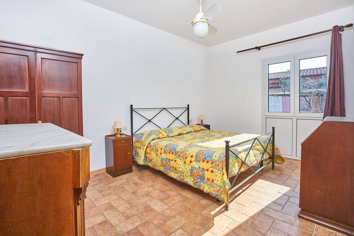 Een slaapkamer met een bed, een houten garderobe en een raam met uitzicht.