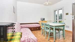 A room with a bed, a table with chairs, a television, and a window. - Appartamenti Il Mare e La Quiete (Portoferraio)
