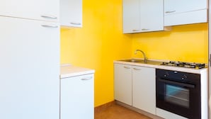 A compact kitchen with white cabinets, a gas stove, and a sink. - Appartamenti Il Mare e La Quiete (Portoferraio)