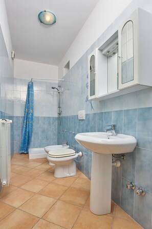 A bathroom with a toilet, sink, and shower.