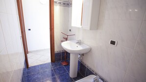 Ein Badezimmer mit einem weißen Waschbecken, einem Spiegel darüber und einem blau gefliesten Boden.