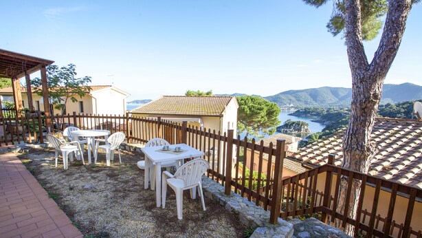 Eine Terrasse mit Sitzgelegenheit, einer Steinsäule und Blick auf die Landschaft.