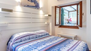 Een slaapkamer met een bed, een wandairconditioner, een raam met uitzicht en een schilderij boven het bed.