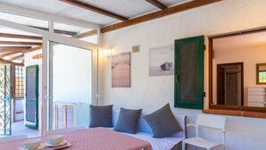 Een gezellige kamer met een bed, een tafel met kopjes en uitzicht op het strand.