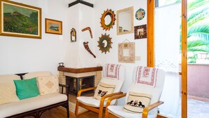 A living room with a fireplace, a sofa, two armchairs, and various wall decorations including framed pictures and mirrors. - Appartamento La Via Del Mare (Rio)