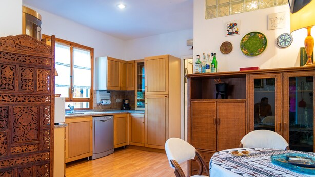 A kitchen with wooden cabinets, a dishwasher, and a dining area with a table and chairs. - Appartamento La Via Del Mare (Rio)