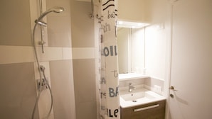 Un baño con ducha, lavamanos y espejo.