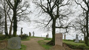 A pathway leading through a cemetery with headstones and statues, surrounded by trees. - Chambres d'Hôtes Au Cœur De Breizh (Plouguernevel)