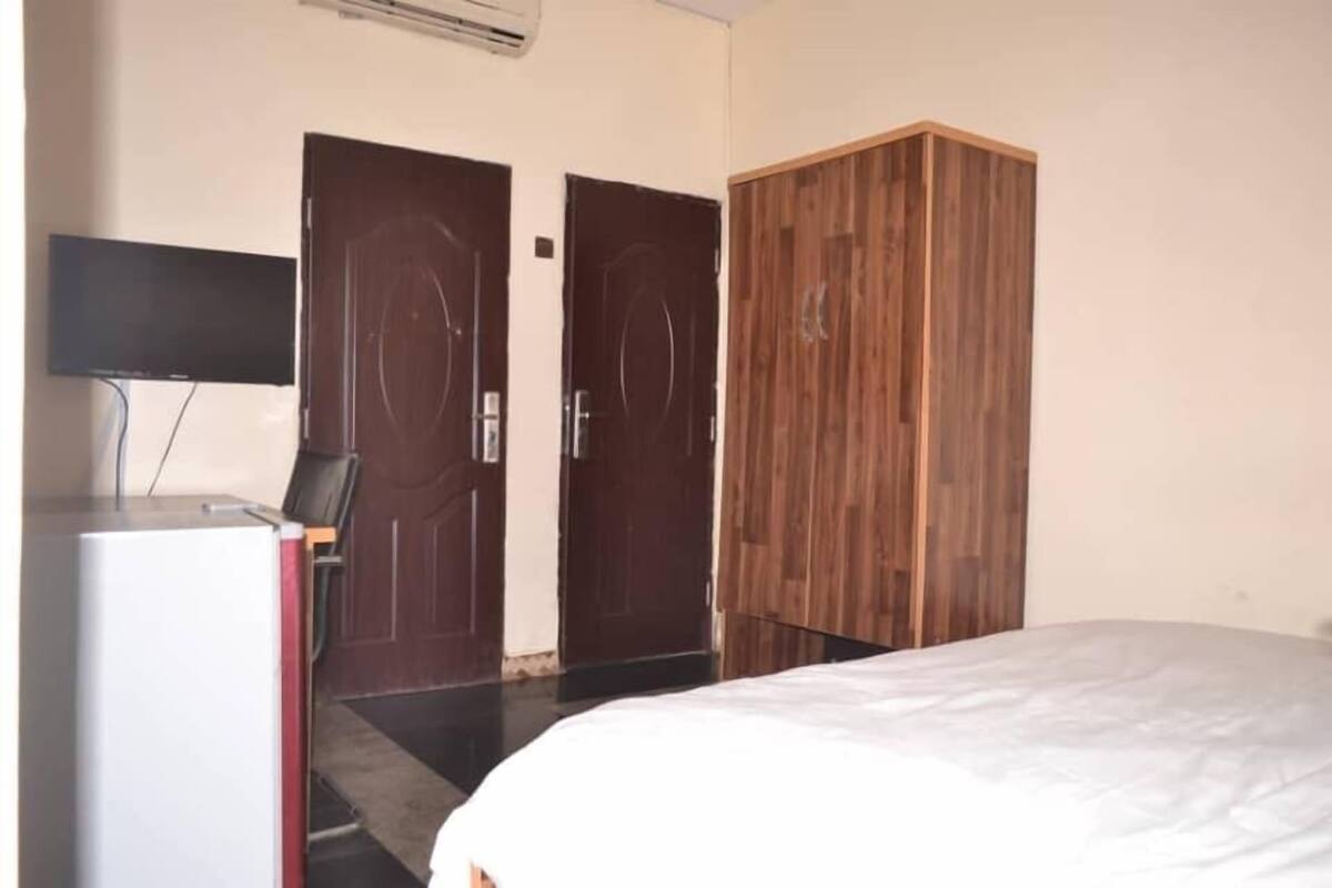 A bedroom with a bed, a wardrobe, a desk with a chair, and two doors.