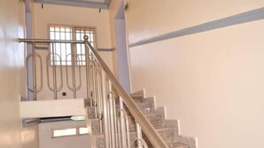 A staircase with metal railings and a handrail, leading to a landing with a window. - Big Pepper Apartment (Abuja)