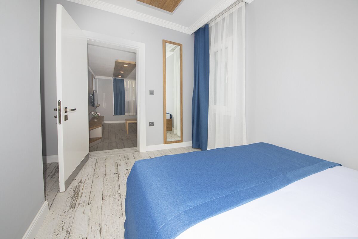 A bedroom with a bed, a mirror, and a door leading to another room.