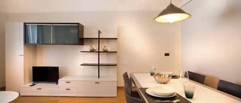 A modern kitchen with a built-in TV, wooden cabinets, and a dining area with a table set for two.