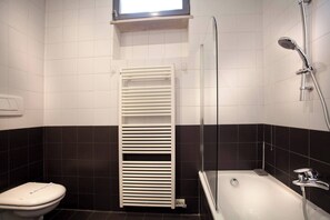 A bathroom with a toilet, a bathtub, and a shower.