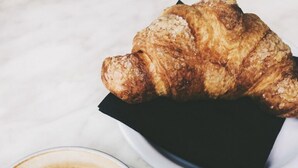 Un croissant et une tasse de café sur une table en marbre blanc.