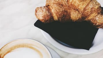Ein Croissant und eine Tasse Kaffee auf einem weißen Marmortisch.