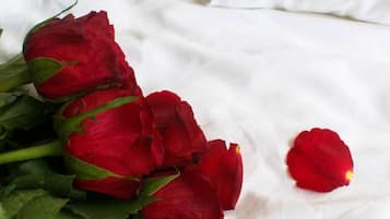 Ein Strauß roter Rosen auf einer weißen Bettdecke.