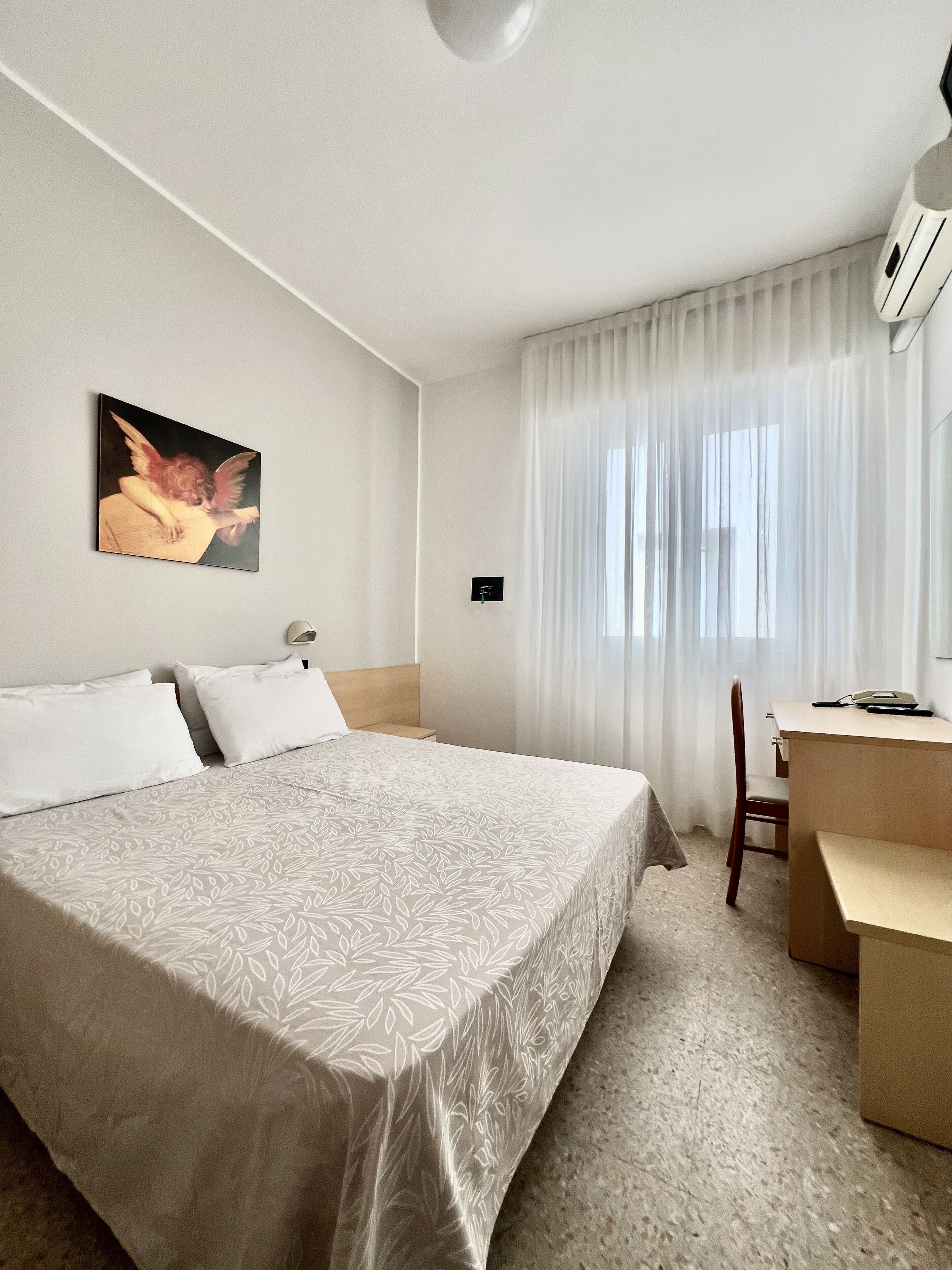 Ein Hotelzimmer mit einem großen Bett, einem Schreibtisch und einem Stuhl.