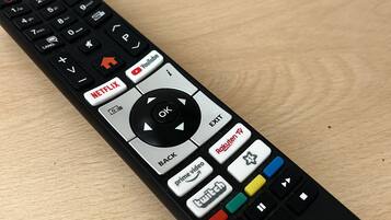 A black remote control with multiple buttons including Netflix, YouTube, and Roku TV.