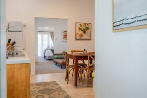 A modern kitchen with a built-in coffee machine, a dining area with a wooden table and chairs, and a living room with a sofa and a bed. - A Touch of the Bahamas on McKenzie MK3 (Cairns)