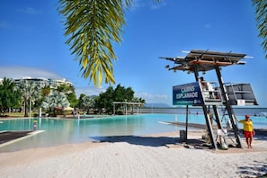 A beachside swimming pool with a lifeguard tower, palm trees, and a sign for Cairns Esplanade. - A Touch of the Bahamas on McKenzie MK3 (Cairns)
