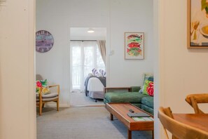 A room with a bed, a sofa, a chair, a wooden bench, a clock, and a painting on the wall.