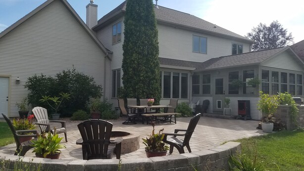 Una casa con un patio cubierto, mobiliario exterior y plantas en macetas.