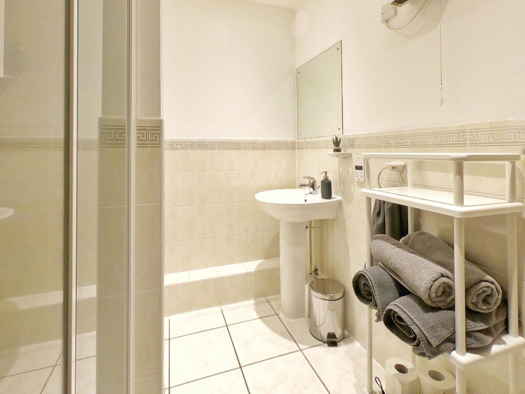 A bathroom with a sink, mirror, and towel rack.