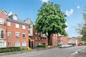 A residential street with brick houses, a large tree, and parked cars. - Central Spacious & Stylish Apartment (Oxford)