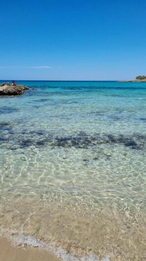 A beach with clear shallow water and a rocky outcrop. - Dolcesosta B&B (Pulsano)