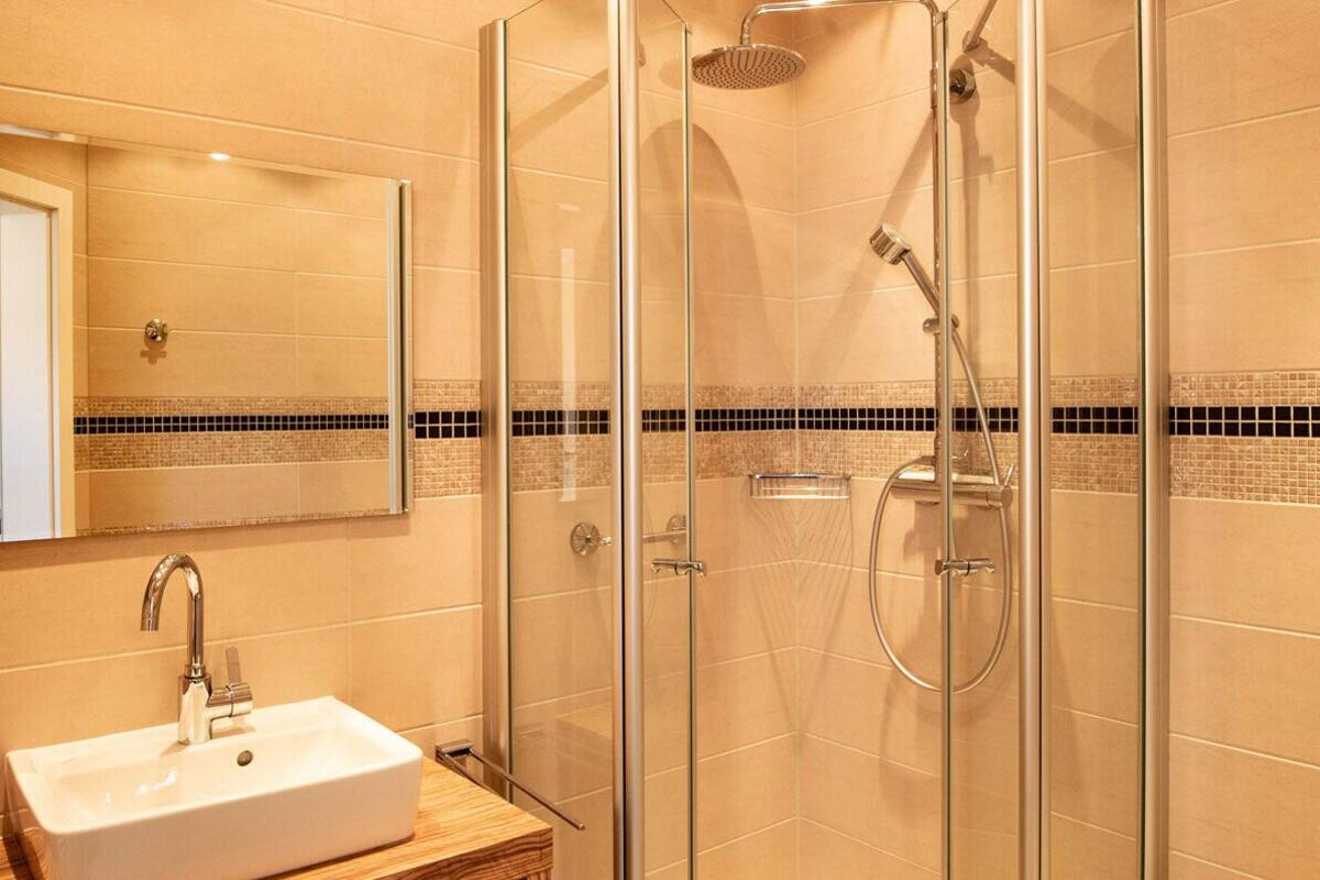 A modern bathroom with a glass-enclosed shower, a white sink, and a tiled backsplash.