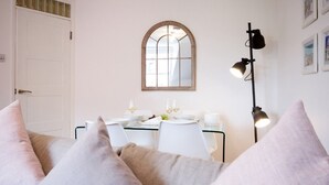 Un comedor con una mesa preparada para dos personas, un espejo sobre la mesa y una lámpara de pie a la derecha.