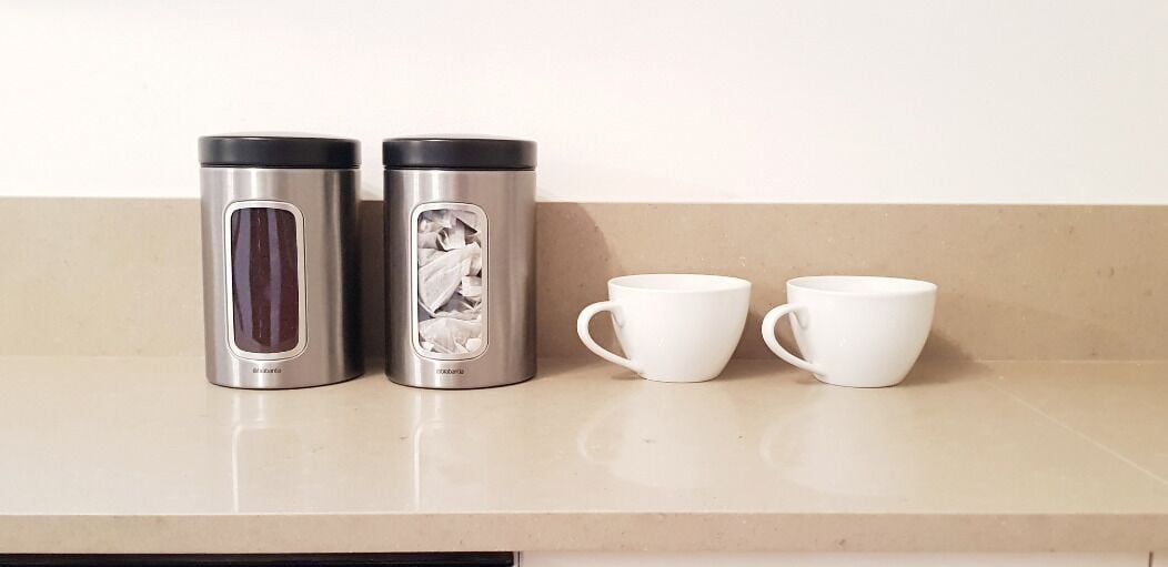 Deux thermos en acier inoxydable et deux tasses en céramique blanche sont posés sur un plan de travail.