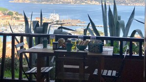 A table with chairs and a view of the sea and a distant mountain range. - Holiday House Palau (Palau)