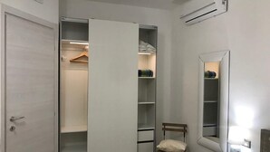A bedroom with a walk-in closet, a bedside table with a lamp, and a chair. - Holiday House Palau (Palau)