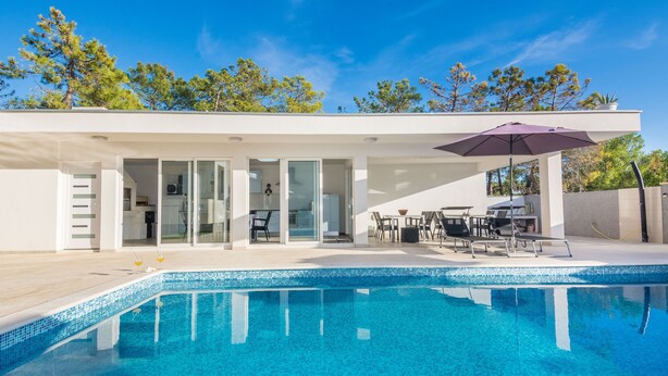 A modern house with a swimming pool, glass doors, and outdoor furniture. - Apartments Olujic (Vir)