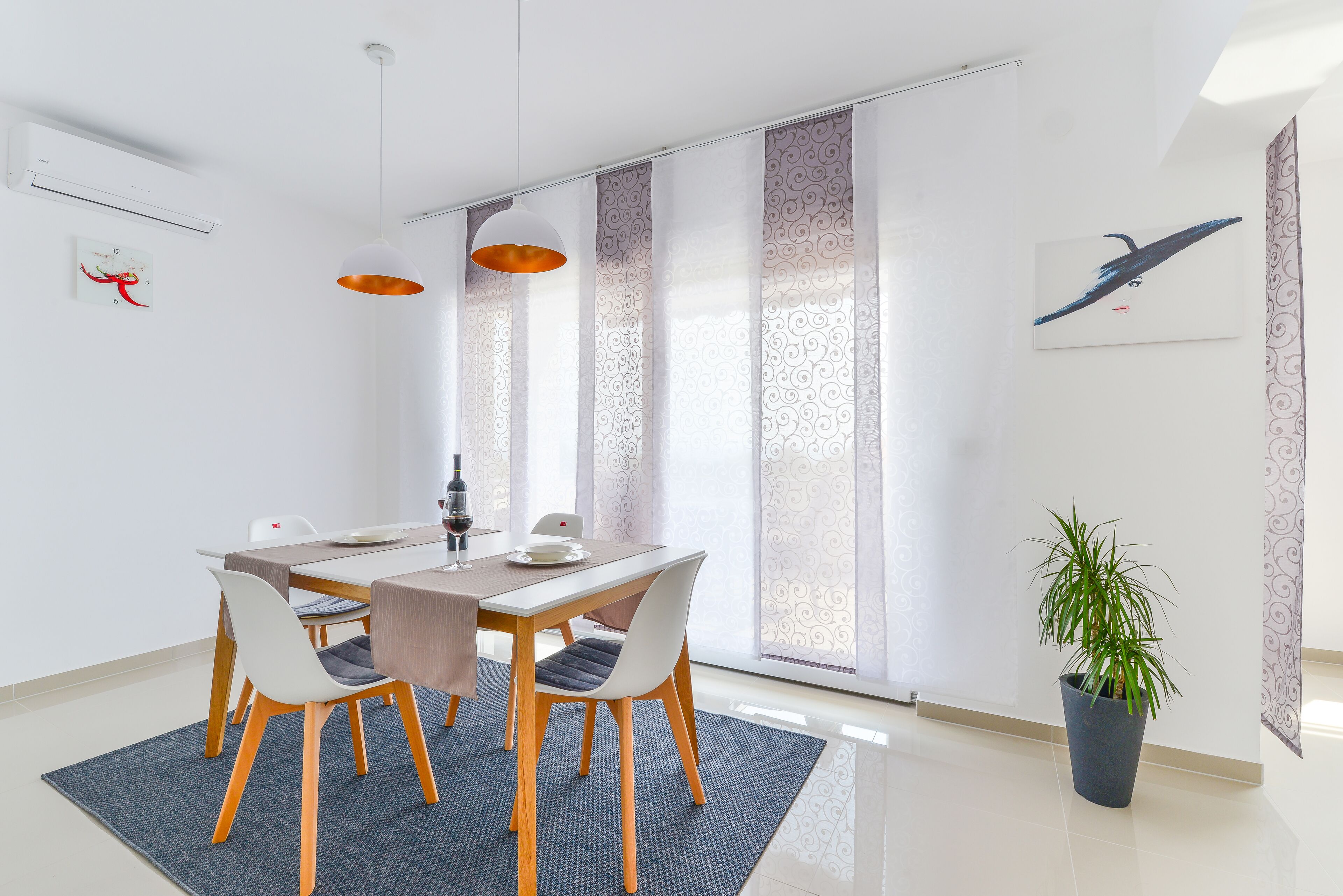 A modern dining area with a table, chairs, and a potted plant.