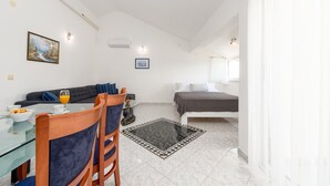 A modern room with a dining table, chairs, a sofa, a bed, and a small rug. - Apartments Pavlak (Vir)