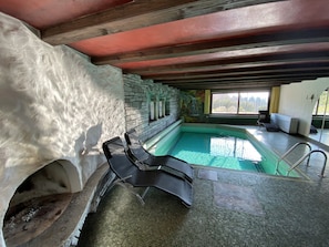 Ein Hallenbad mit Steinwänden und Blick ins Freie.