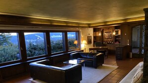 A spacious living room with a large window, a fireplace, and a dining area. - Villa in the Black Forest with indoor pool (Falkau)