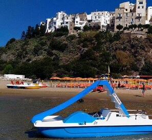 Un bote amarrado cerca de una playa, con un edificio al fondo.