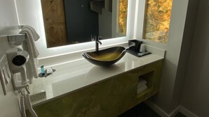 A bathroom with a modern sink, a large mirror, and a view of the outside. - Palace Inn (Humble)