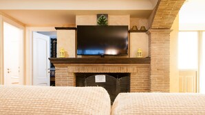 A living room with a fireplace, a flat-screen TV mounted above it, and two beige sofas. - Casa Vacanza Polifemo Loft (Sperlonga)