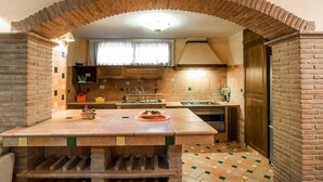 A kitchen with a brick archway, wooden cabinets, and a tiled floor. - Casa Vacanza Polifemo Loft (Sperlonga)